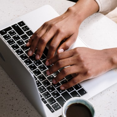 En kvinna som skriver på en laptops tangentbord. 