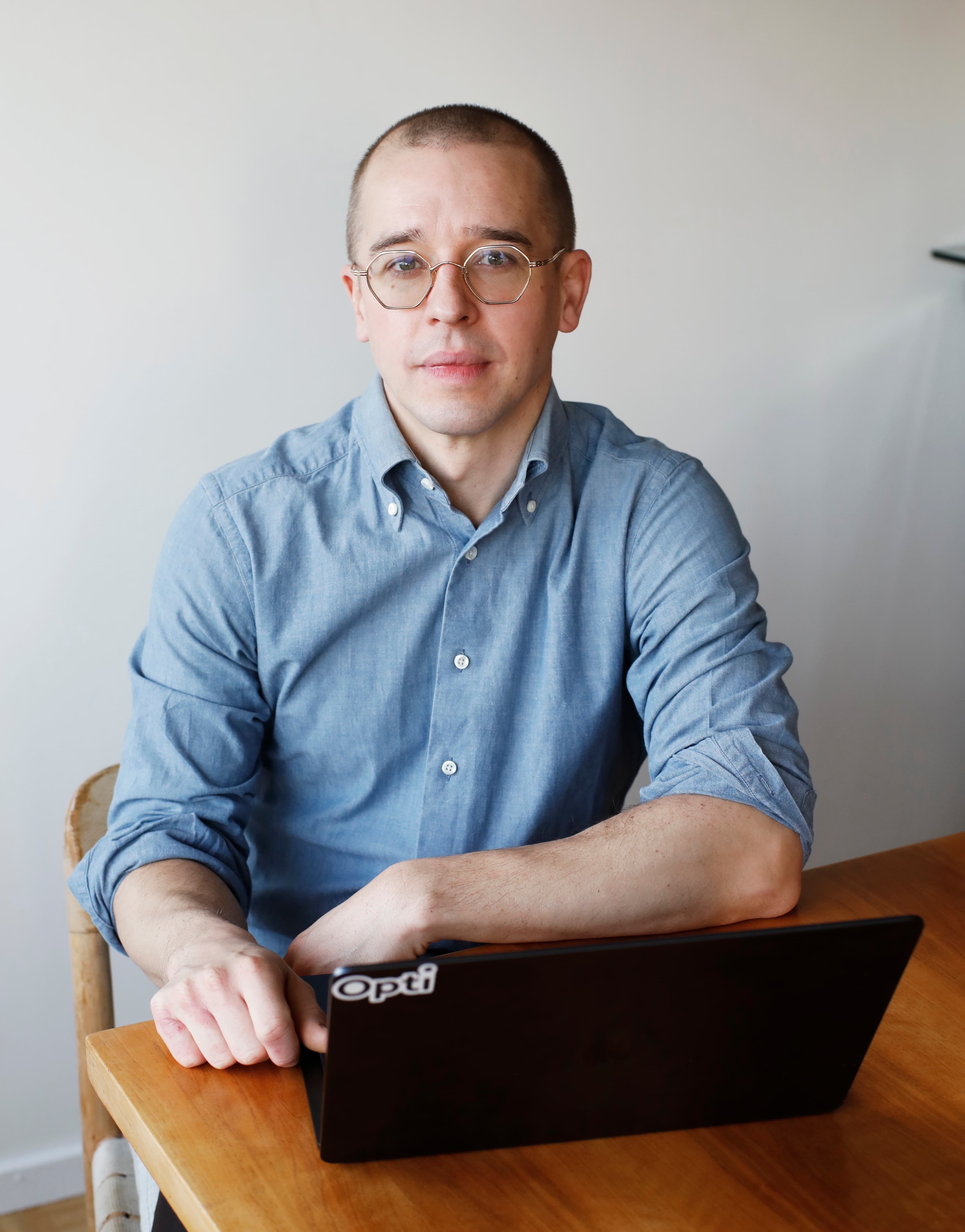 Man med glasögon och ljusblå skjorta, sittandes vid ett bord.