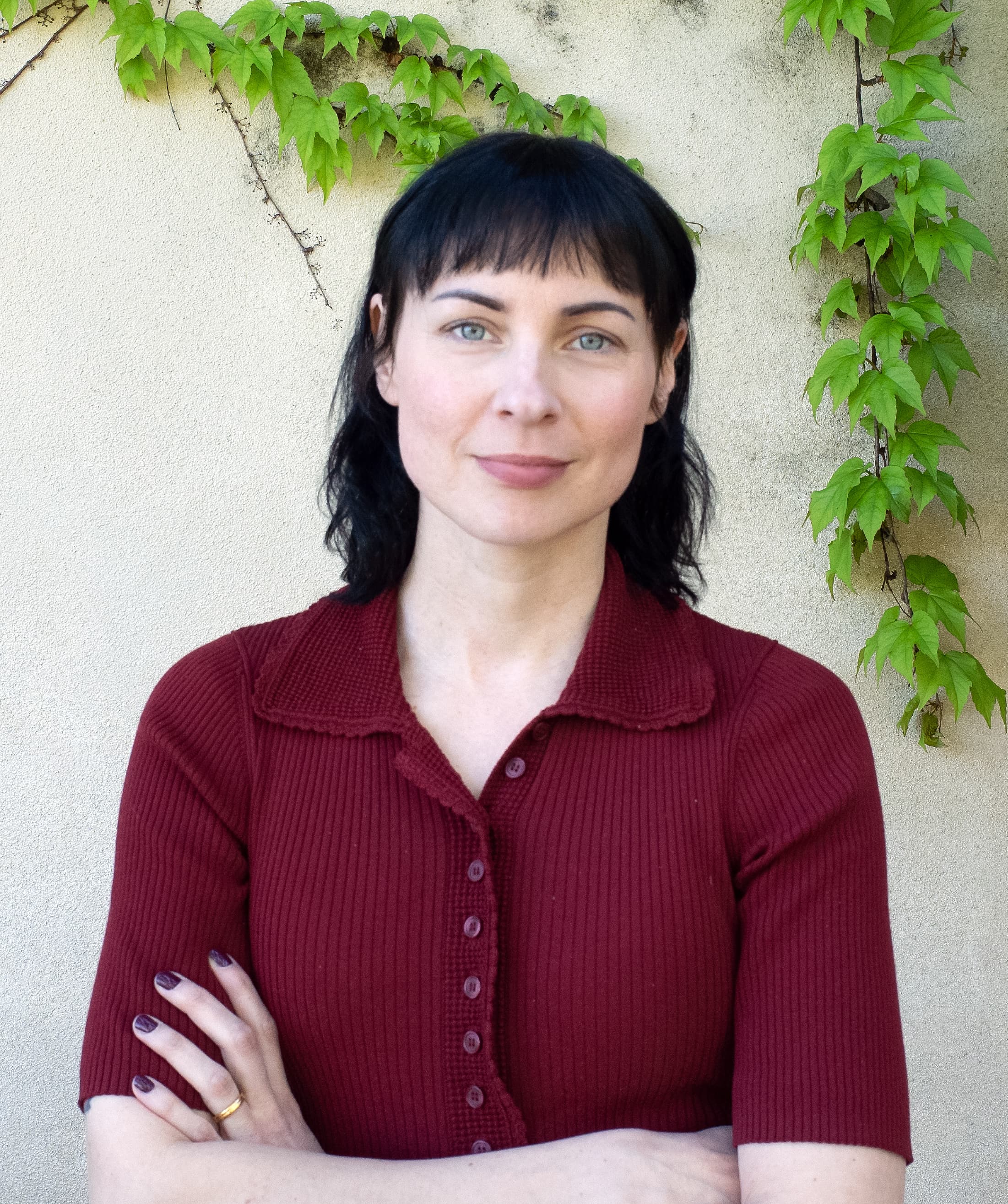 Kvinna med svart hår och röd t-shirt håller armarna i kors.