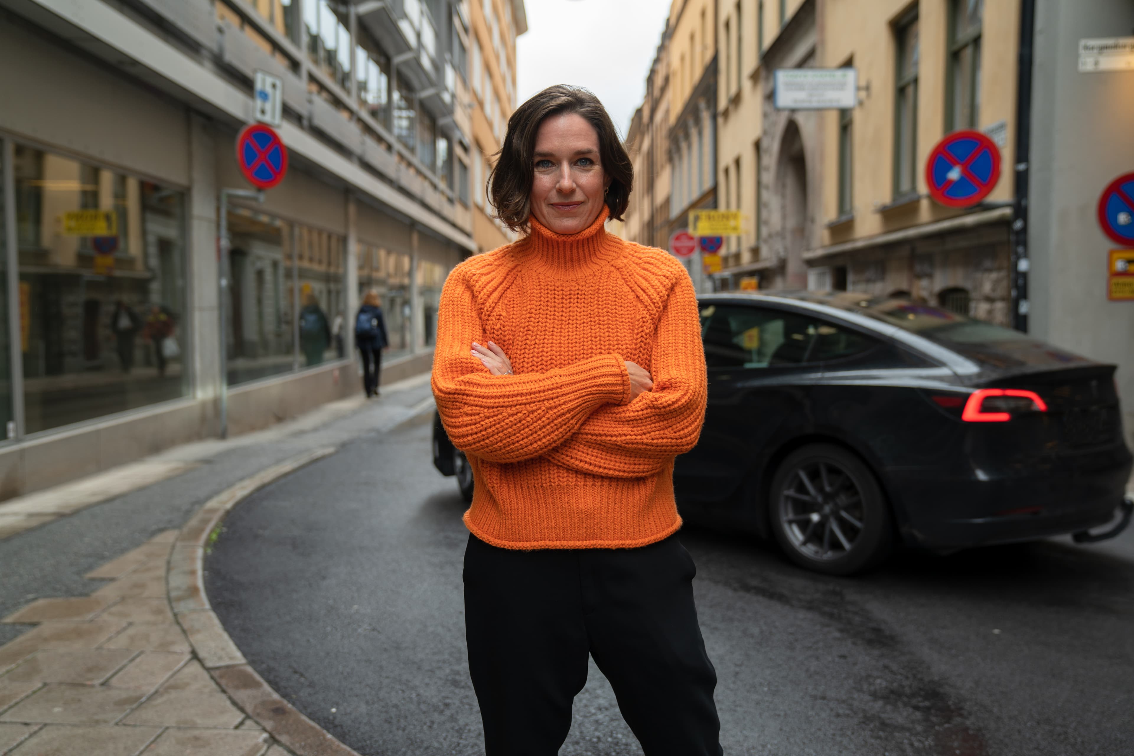 Kvinna med brunt hår och orange tröja poserar för kameran.