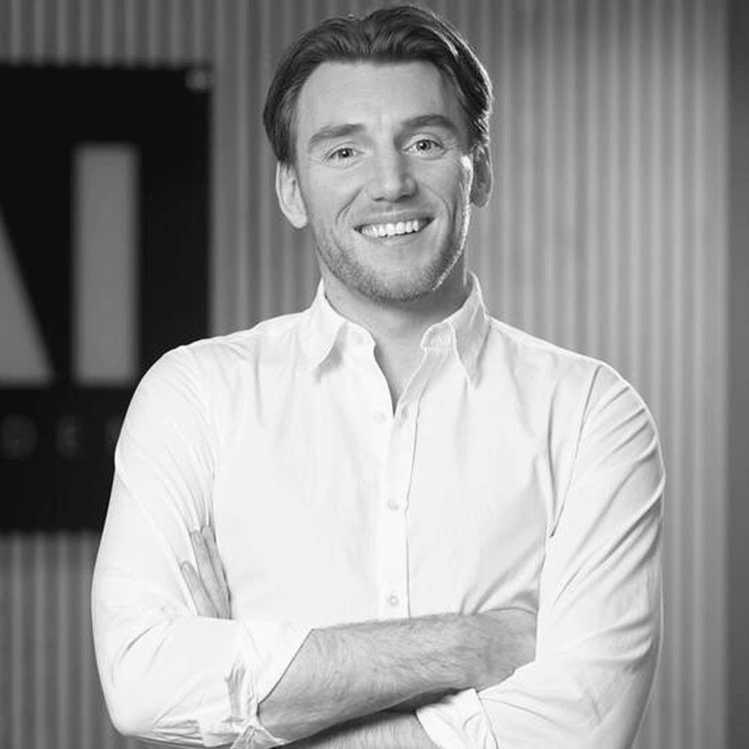 Man i 40 års åldern med vit skjorta. Håller armarna i kors och ler mot kameran.