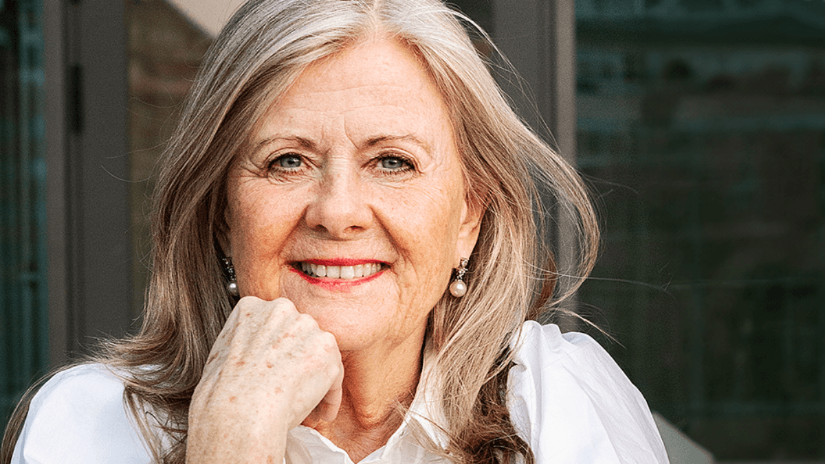 Kvinna med rött läppstift och vit skjorta poserar för kameran.