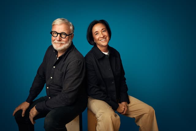 Kvinna och man sitter på en pall, ler in mot kameran.