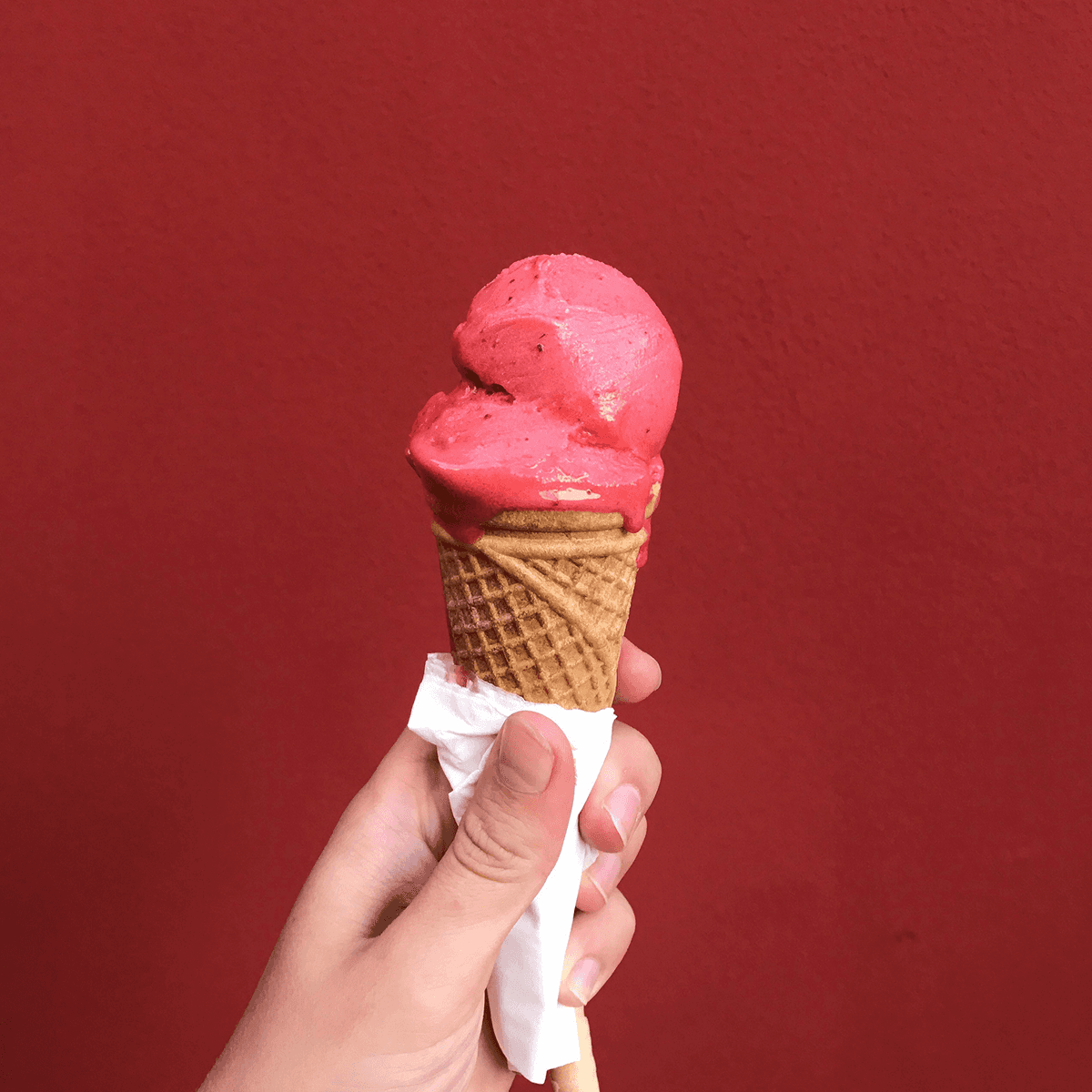 En hand som håller en rosa glass.