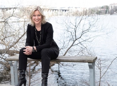 Eva Willstrand sitter på en bänk vid ett vattendrag