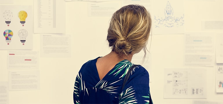 En kvinna med mellanblont uppsatt hår i knut iklädd en mörkblå topp