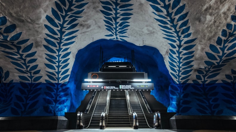En tunnelbaneperrong med blåa väggar och två rulltrappor